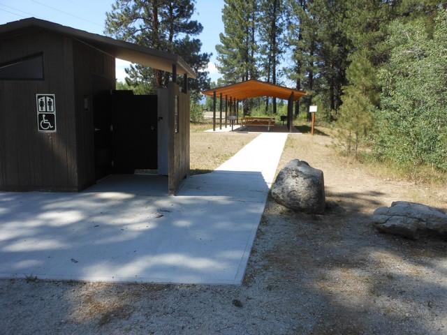 picture showing View of latrine and picnic shelter connected by sidewalk.