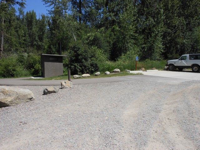 picture showing Nice parking pad and paved trail to latrine.  The paved trail continues off to the left to a picnic shelter and fishing platform.  Look at the other pics.