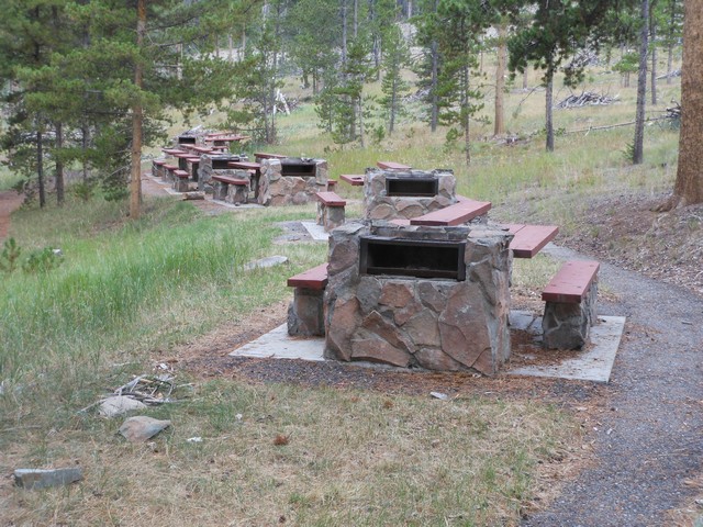 picture showing Gang of unique individual picnic tables with built-in fire-grills.  Notice the paved trail system accessing these tables.