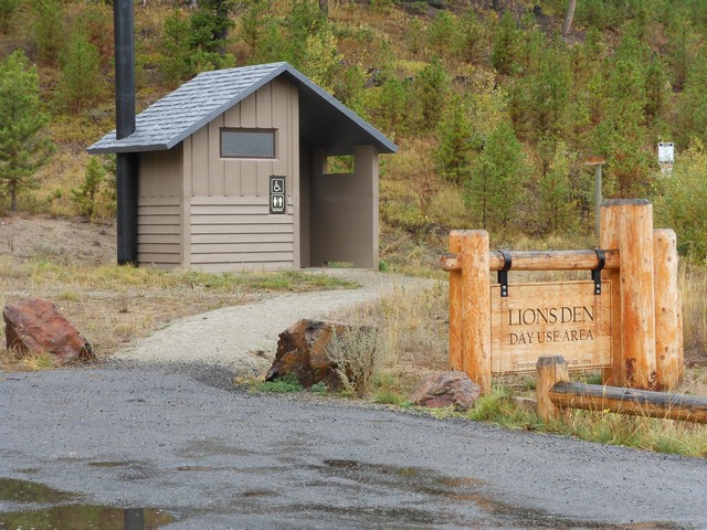 picture showing At the Lion's Den, a nice paved parking lot.  The trail to the latrine is gravel with a portion of it having a cross slope of 3.9 %.