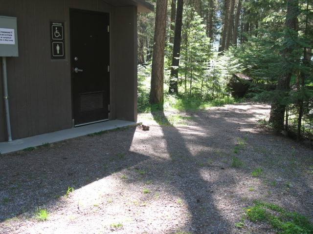 picture showing Unfortunately, the most difficult access routes in the Bay Loop are those leading to the bathrooms with flush toilets.  This picture shows the most difficult access route with a short 6.5 degree slope on firm and stable gravel with a 2.5 degree cross slope and 36 inch clear tread width.  There is also up to a 3 inch step from the access route onto the concrete pad of the bathroom.  Access to the other bathroom on the Bay Loop (also with flush toilets) is better, and access to this bathroom is better if approached from a different direction.