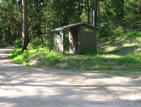 picture showing The other bathroom in the campground is located along the road and parking area in a completely inaccessible location without an an access route of any kind.  Campsite numbers 1 and 2 are located up the steep hill to the right of the bathroom, and both are also completely inaccessible.