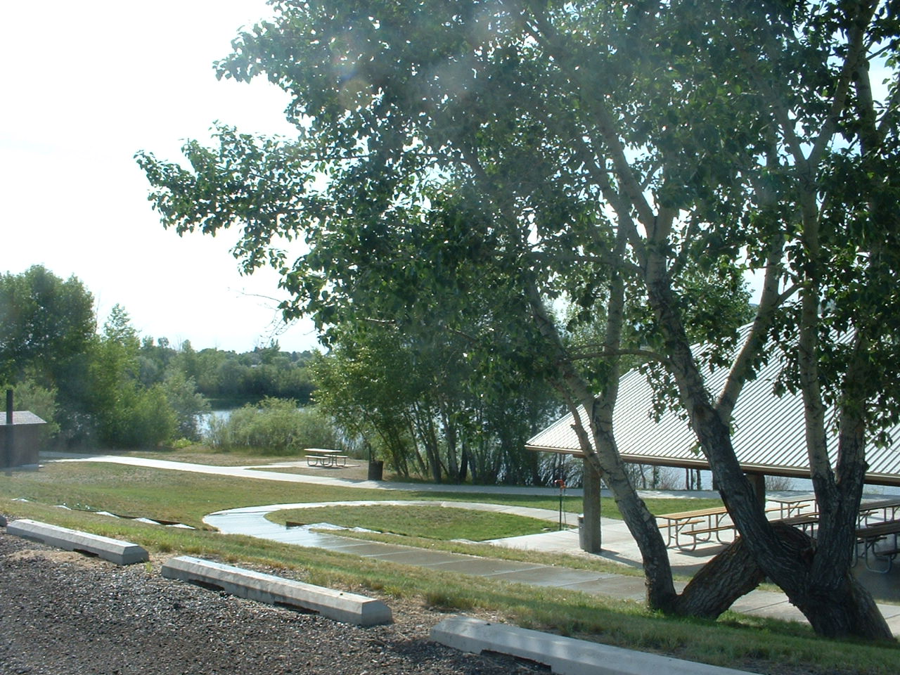 picture showing View of group picnic shelter, paved pathways, and a single picnic table at Spring Meadow Lake.
