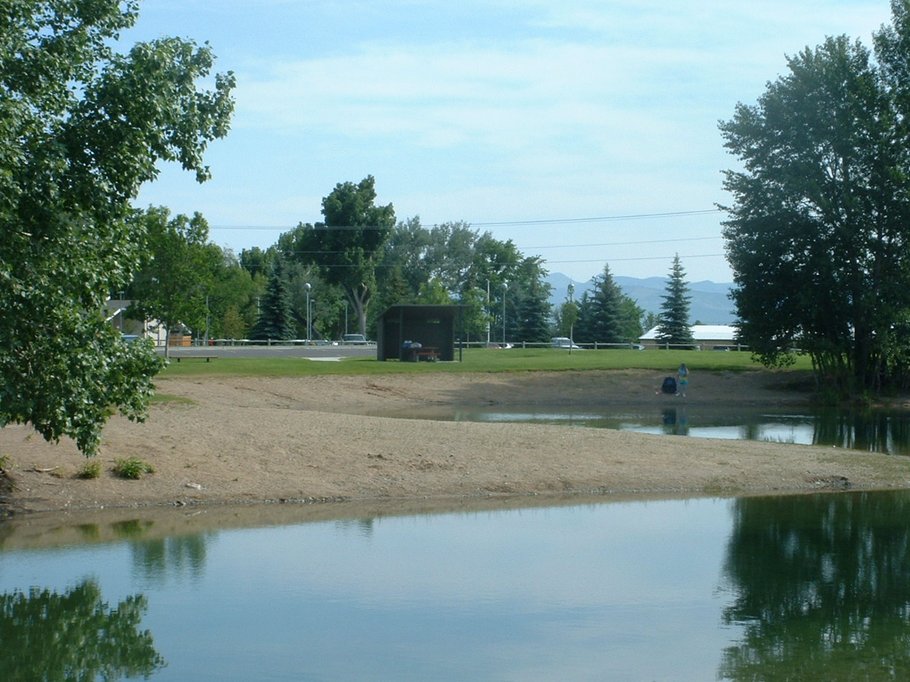 picture showing Picture of Spring Meadow Lake with one sheltered picnic table in the background.